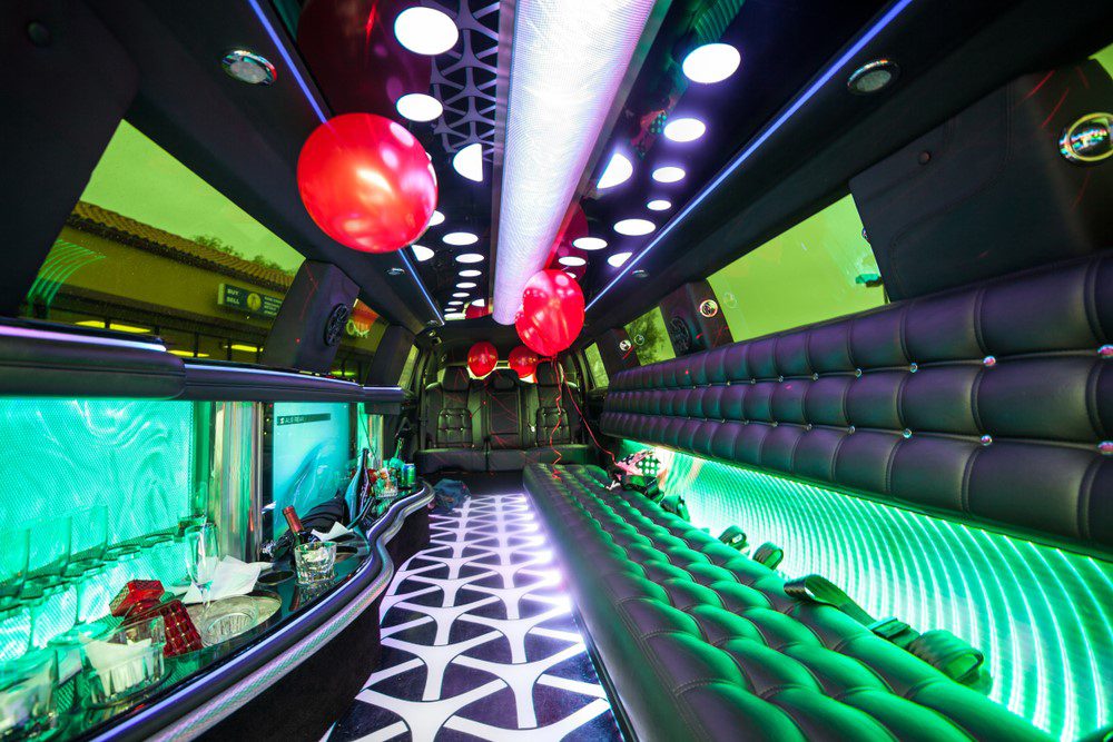 A party bus with green lights and black walls.