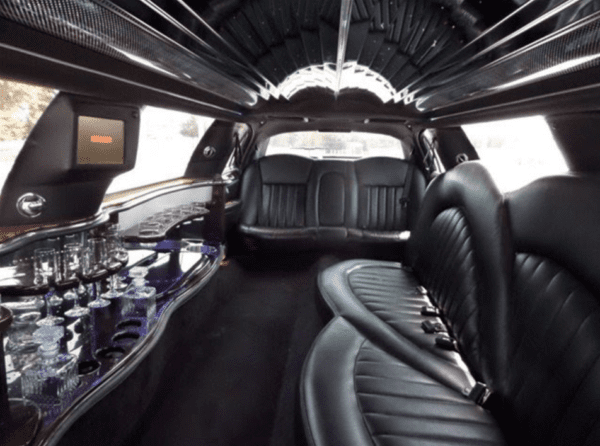 A limo car with black leather seats and the door open.