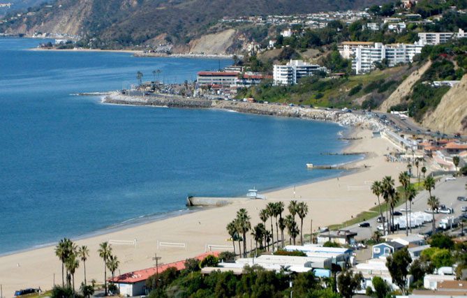 A beach with many people on it and some buildings