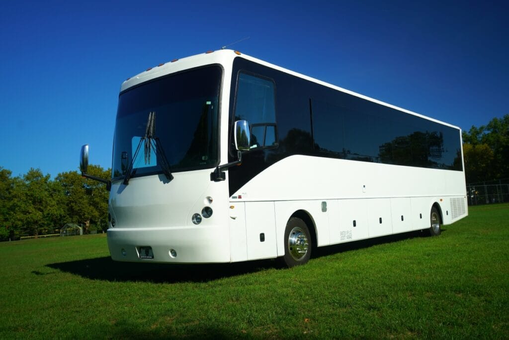 A white bus is parked in the grass.