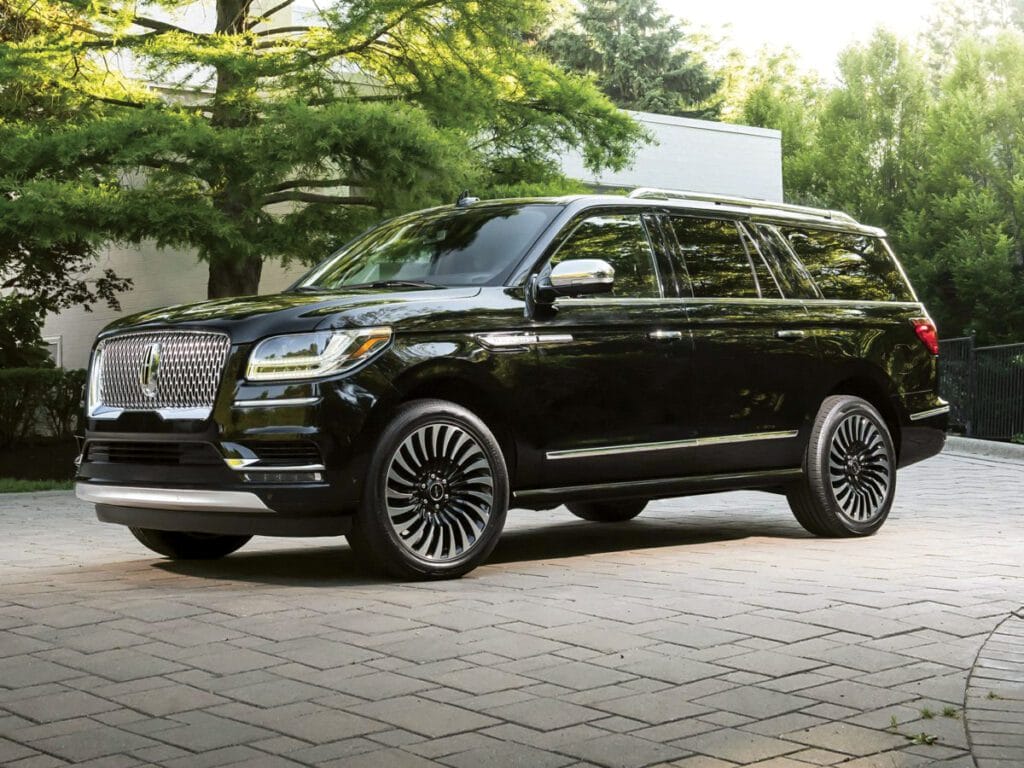 A black lincoln navigator parked on top of a brick road.