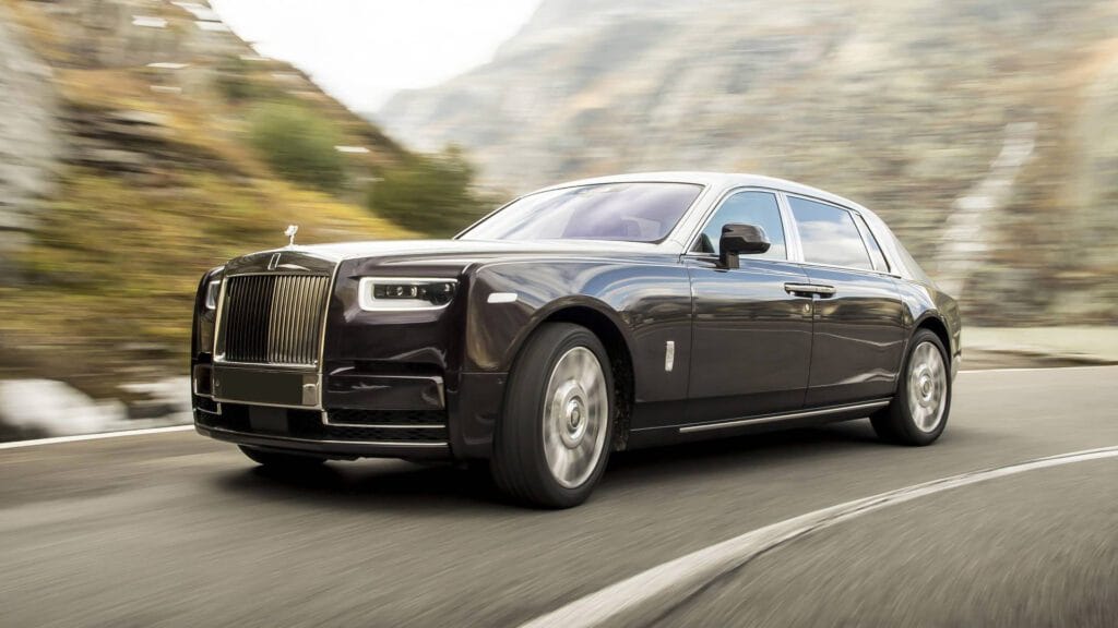 A rolls royce is driving down the road.