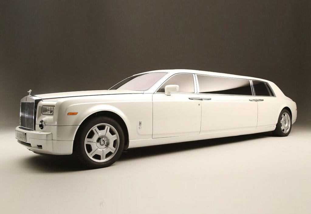 A white limo is parked in front of the wall.