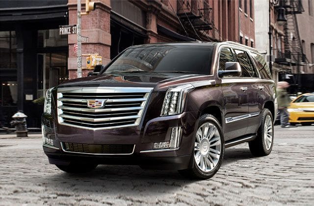 A brown cadillac escalade is parked on the street.