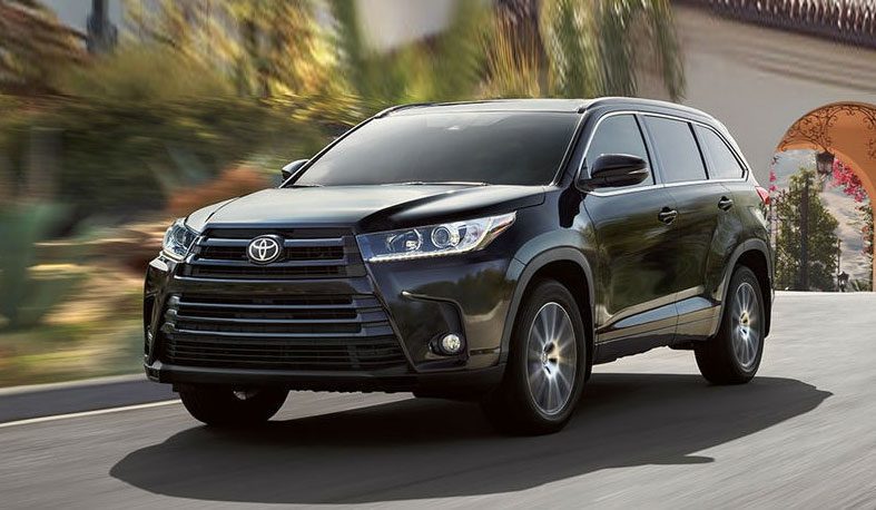 A black toyota highlander driving down the street.
