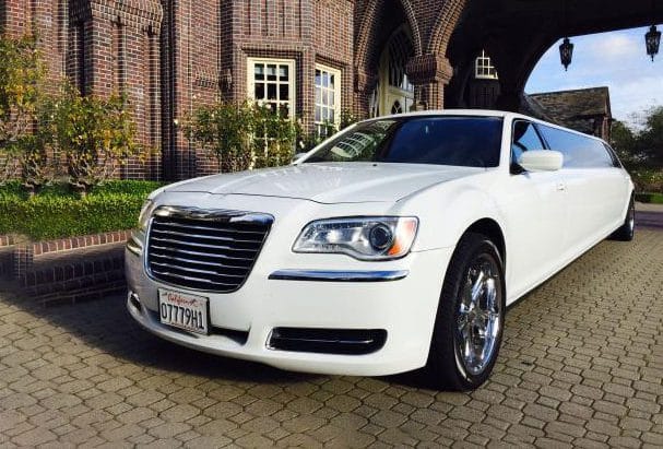 A white limo parked in front of a brick building.