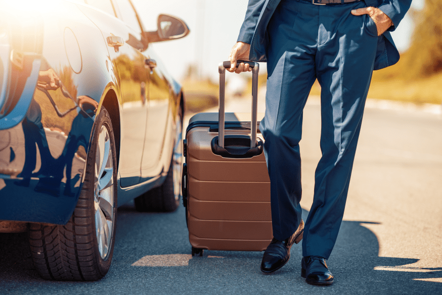 A man with luggage standing next to a car.