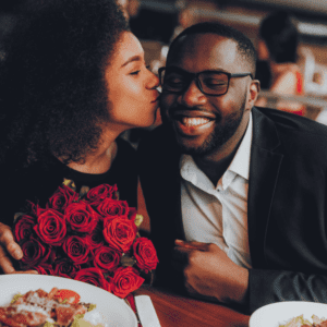 A man and woman kissing at the table.