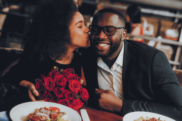 A man and woman kissing at the table.