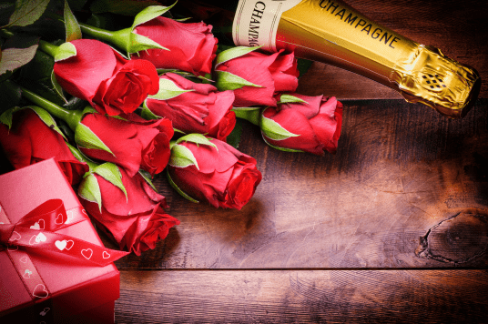 A bunch of roses and champagne on a table.
