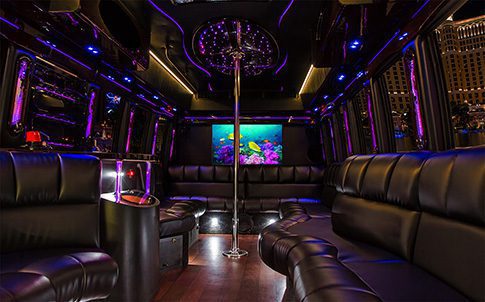 A room with purple lighting and black leather furniture.