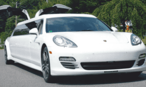 A white car driving down the street near trees.