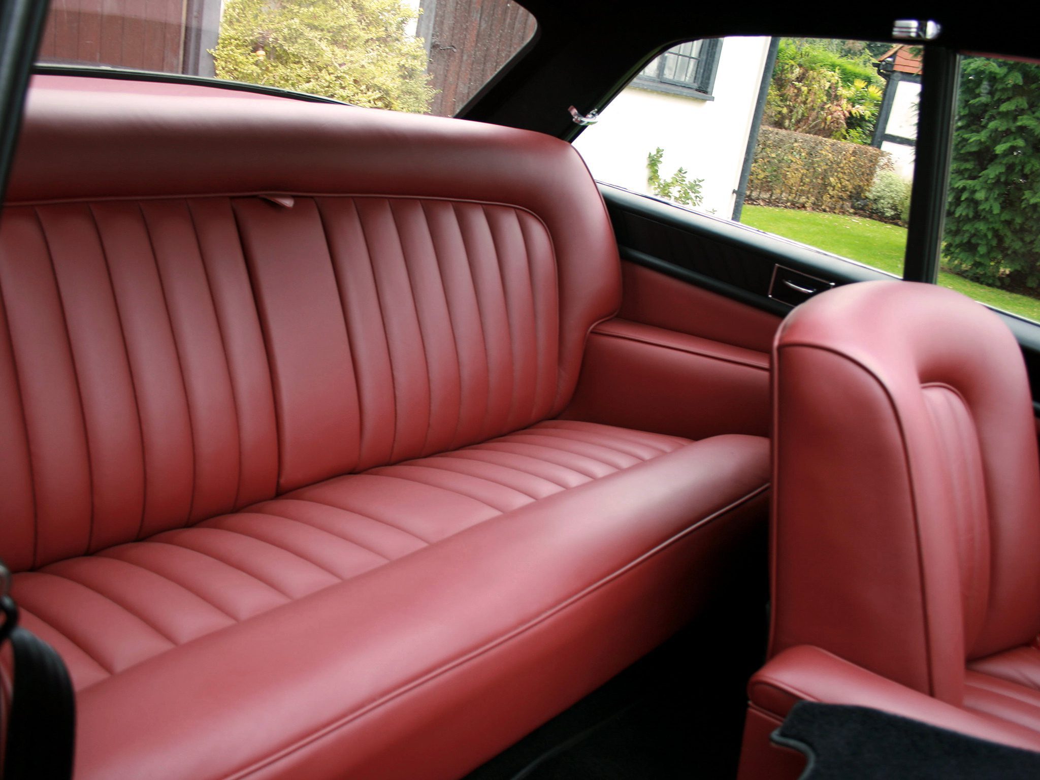 A red leather car seat in front of a window.