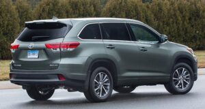 A green toyota highlander parked on the side of a road.