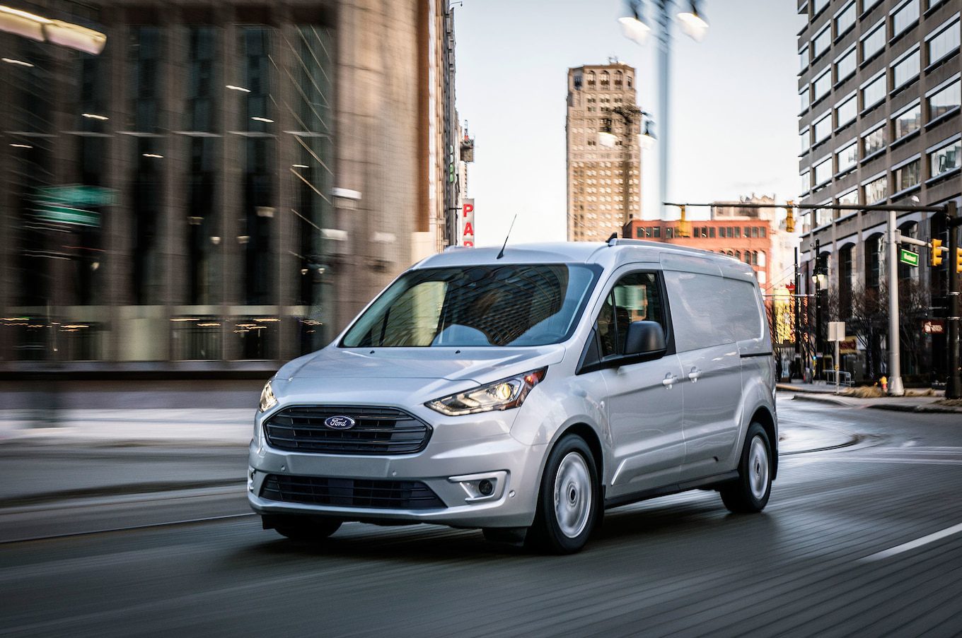 A silver van is driving down the street.