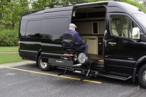 A man in a wheelchair is sitting on the back of a van.