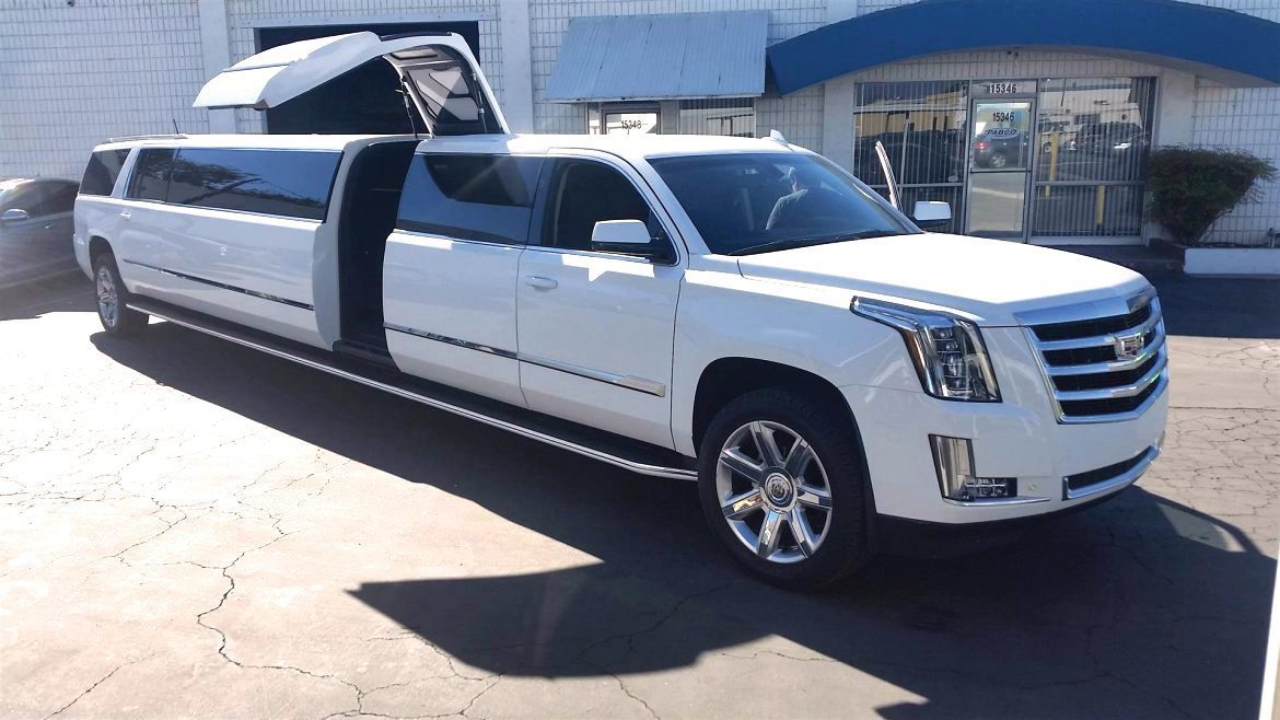 A white limo is parked in front of a building.