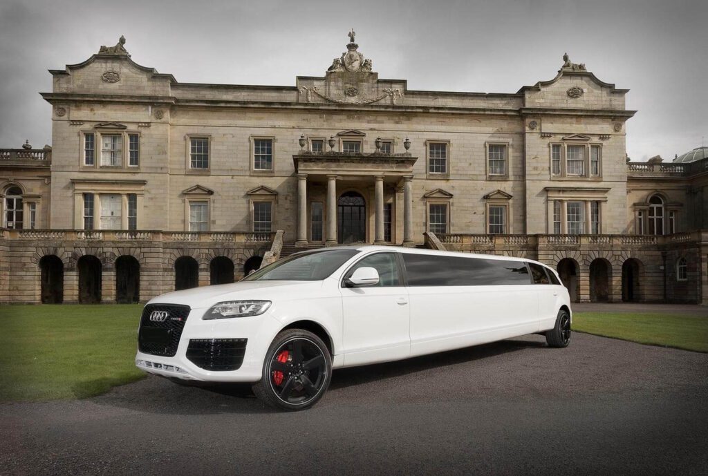 A white limo parked in front of a large building.