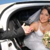 A bride and groom in the back of their car.