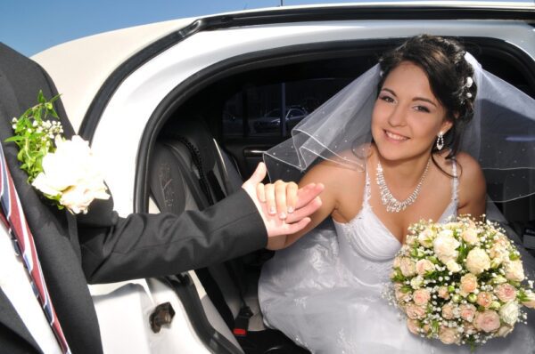 A bride and groom in the back of their car.