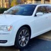 A white limo parked in front of some trees.