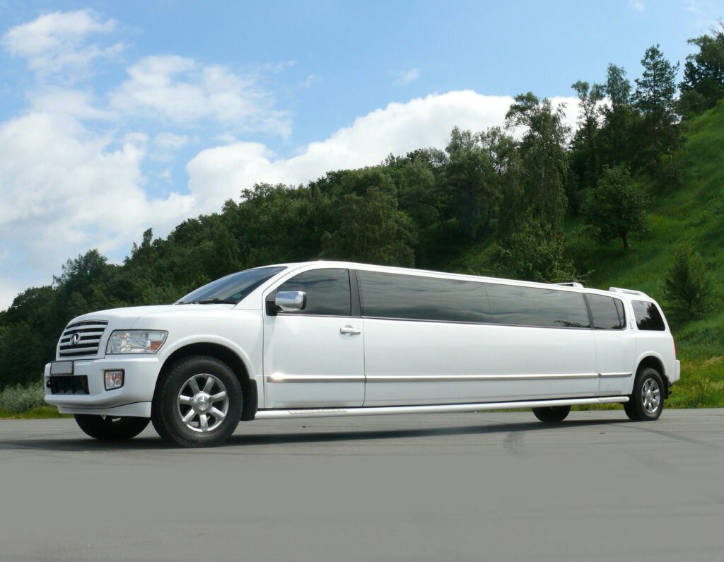 A white limo is driving down the street.