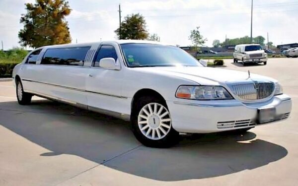 A white limo is parked in the parking lot.