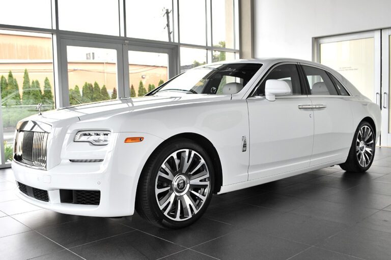 A white rolls royce parked in front of a window.