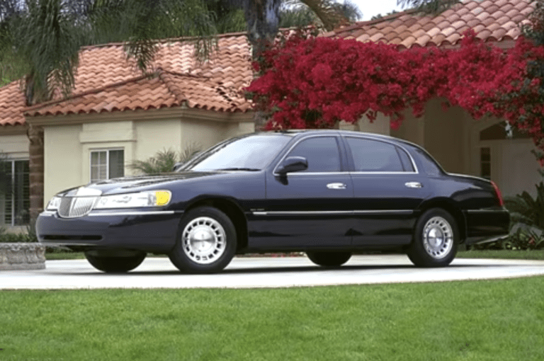 A black car parked on the grass near a house.