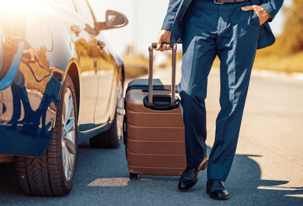 A man with luggage standing next to a car.