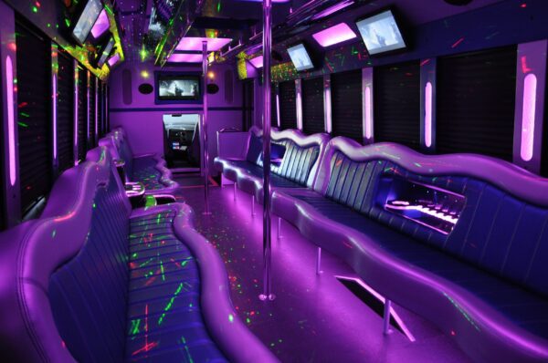 A purple party bus with neon lights and tables.