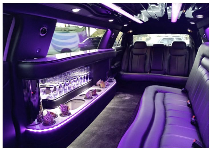 A purple limo with the lights on.