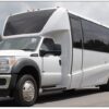 A white limo bus parked on the side of a road.