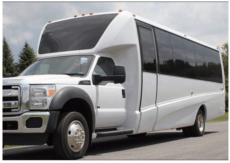 A white limo bus parked on the side of a road.