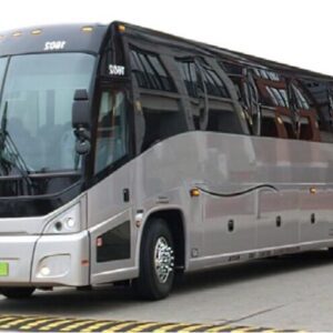 A silver bus is driving down the street.