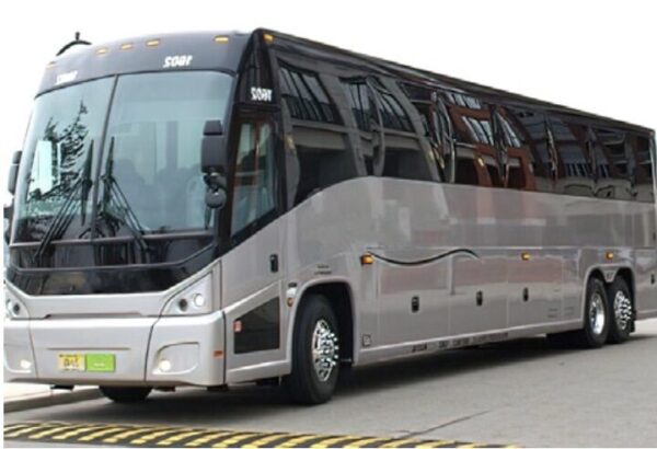 A silver bus is driving down the street.