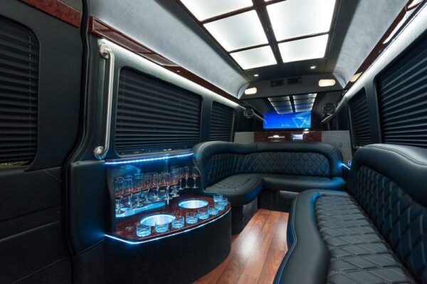 A party bus with black leather seats and blue lighting.