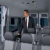 A man in suit and tie standing inside of an empty van.