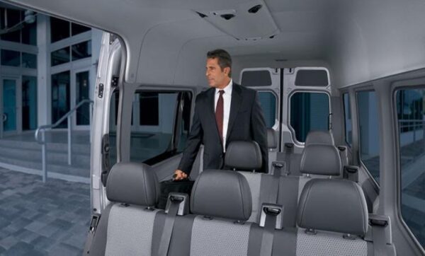 A man in suit and tie standing inside of an empty van.