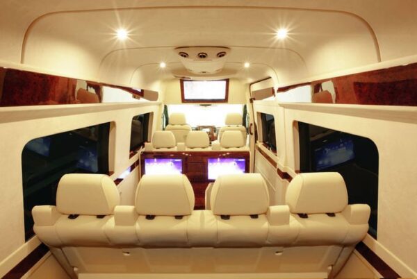 A view of the inside of a bus with white leather seats.