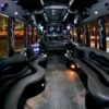 A party bus with black leather seats and lights on the ceiling.