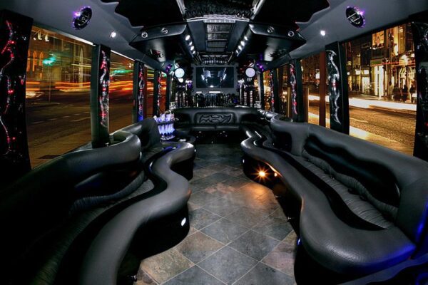 A party bus with black leather seats and lights on the ceiling.