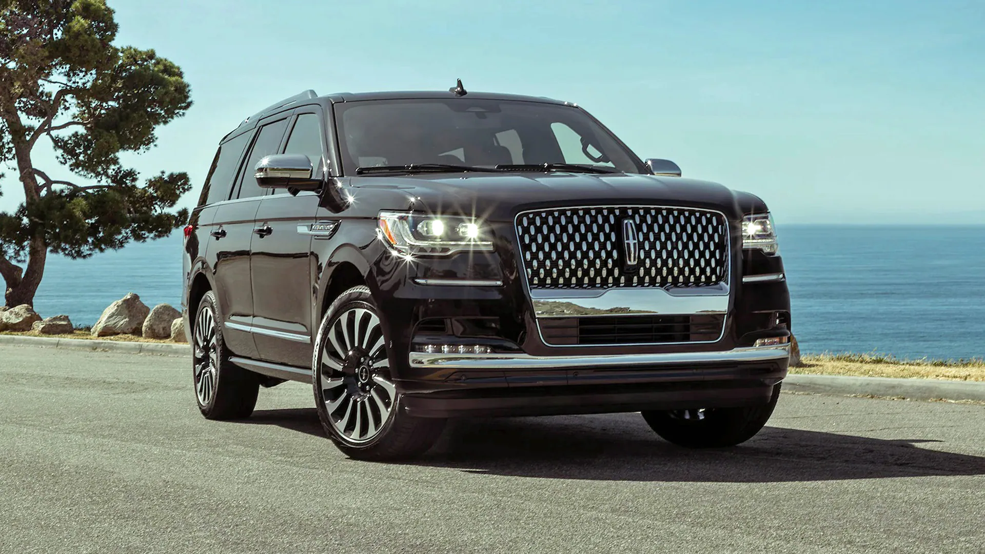 A black lincoln navigator is driving down the street.