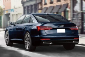 A blue car driving down the street in front of buildings.