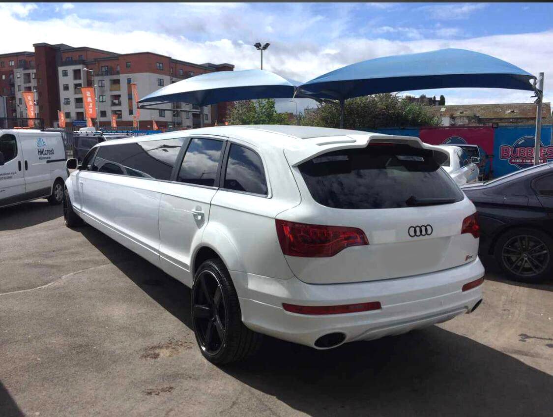 A white limo parked in the parking lot.