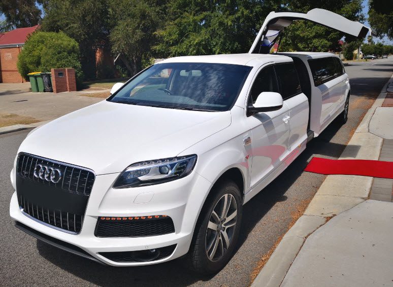 A white car with its door open parked on the side of the road.