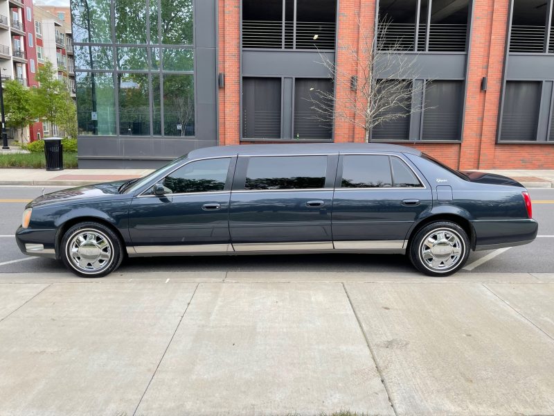 A long limo parked in front of a building.