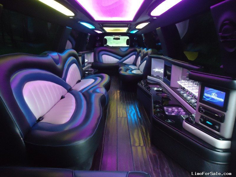 A limo with purple lights and a black leather couch.