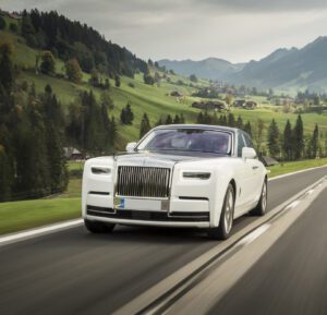 A white rolls royce driving down the road.