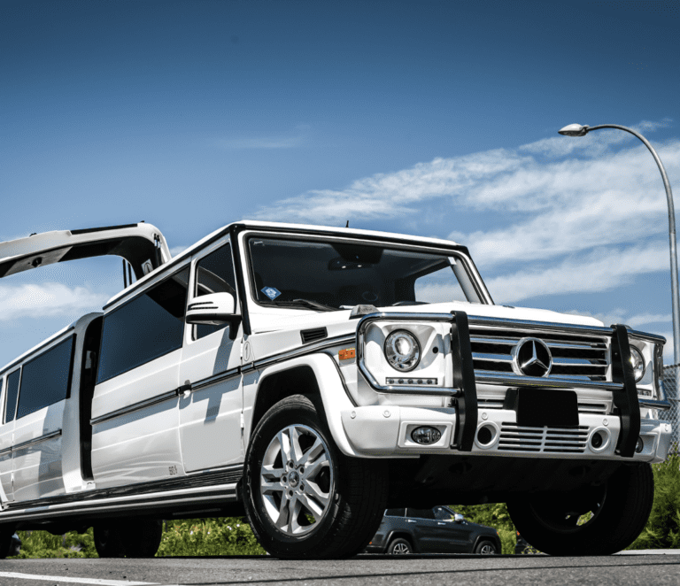 A white mercedes benz limo parked on the side of a road.